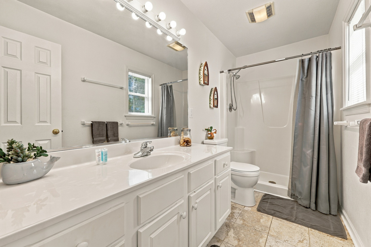 Bright full bath with a walk-in shower and a long vanity.