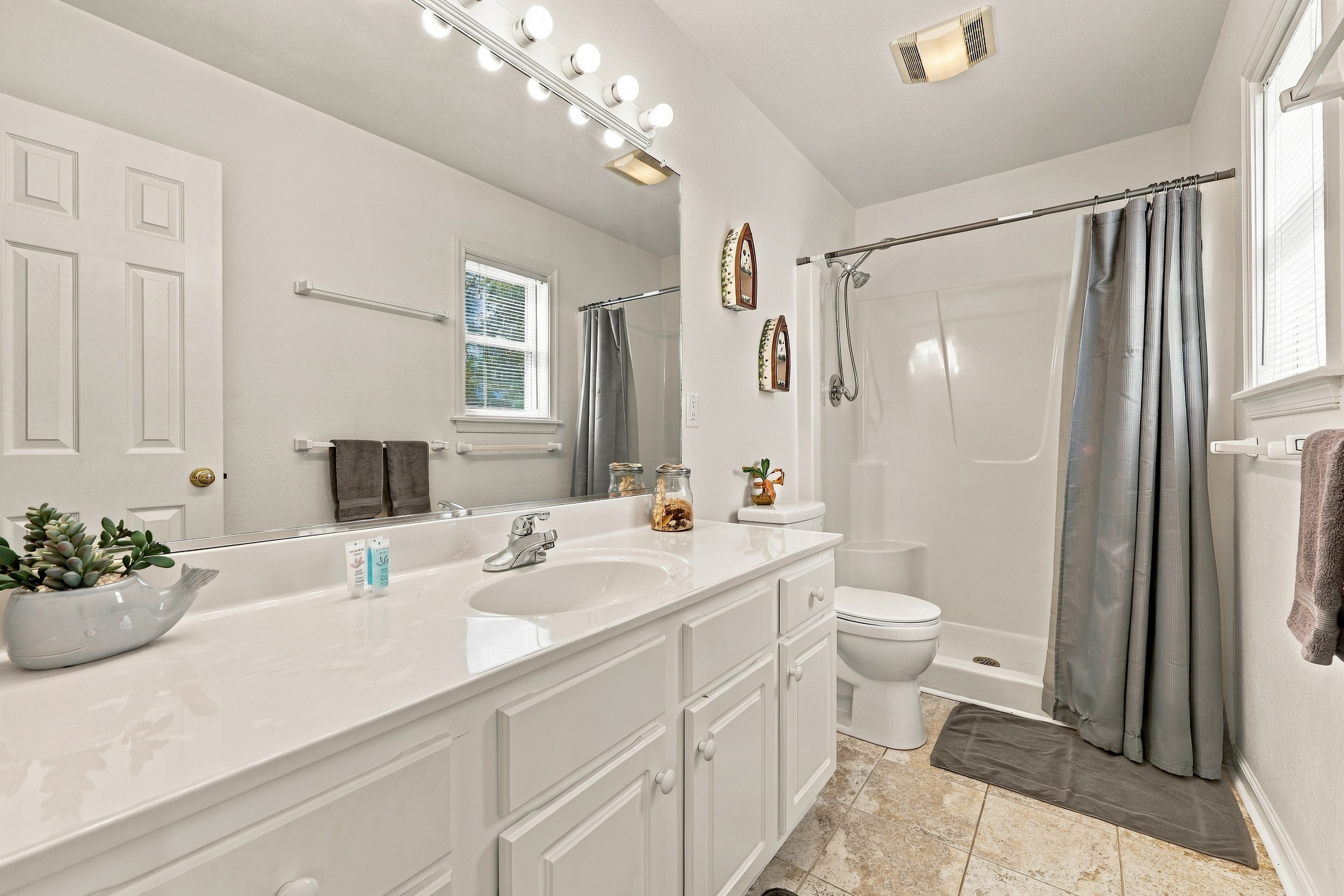 Bright full bath with a walk-in shower and a long vanity.