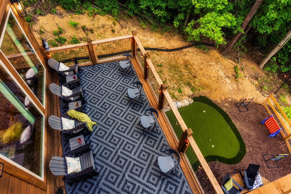 Spacious balcony with outdoor seating, nature views, string lights, fire pit, mini golf, and hot tub.