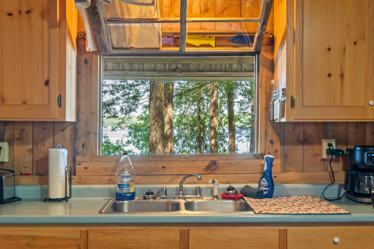 Convenient kitchen pass-through window at Loonrise Point! Hinged window above the sink opens to the screened porch for easy dish clearing and meal serving. Enjoy tree and lake views on Beech Hill Pond in Otis, ME while prepping meals!