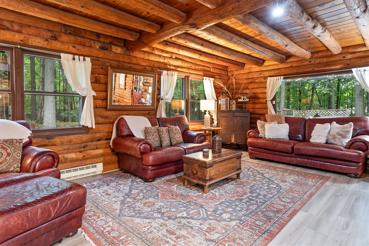 A cozy log cabin living room featuring rich wood beams, leather seating, and natural light pouring through the windows—perfect for relaxing after a day outdoors.