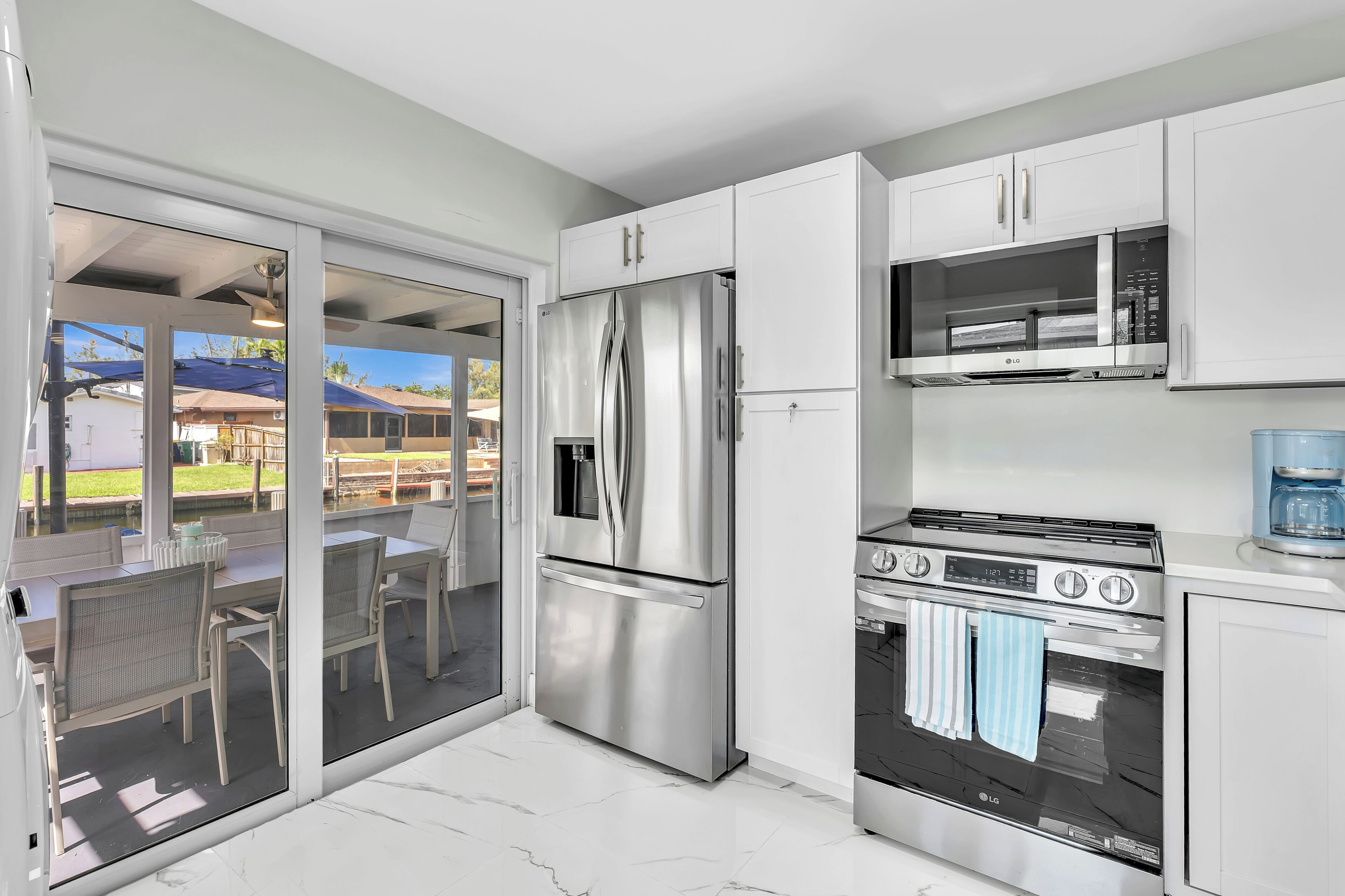 Bright, fully stocked kitchen with LG stainless steel appliances and direct access to the waterfront patio.