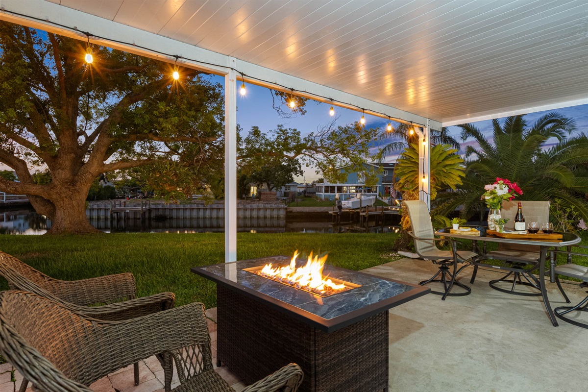 As evening falls, string lights cast a warm glow over the patio, creating a magical ambiance for dinner parties or quiet moments by the fire pit.
