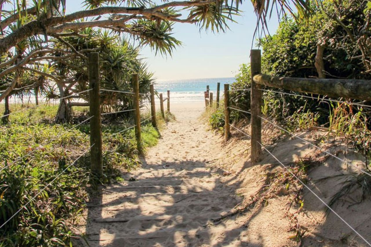 This nearby beach access gives Aaron's Beachside Boat House a direct coastal connection, with a simple sandy track leading through native vegetation to the shoreline.