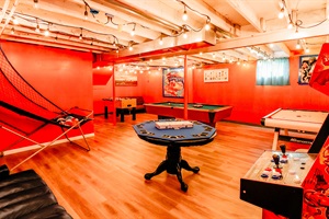 Against a backdrop of a vibrant red wall, a sleek pool table and a lively foosball table stand ready for friendly competition and laughter. It's the ultimate entertainment space where every game is a chance to make memories.