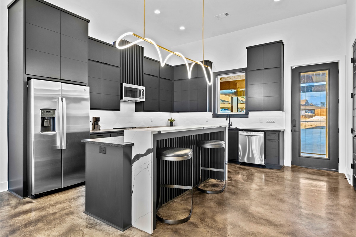 This modern kitchen combines sleek cabinetry, bold gold lighting, and a spacious layout, creating a stylish hub for cooking and entertaining.