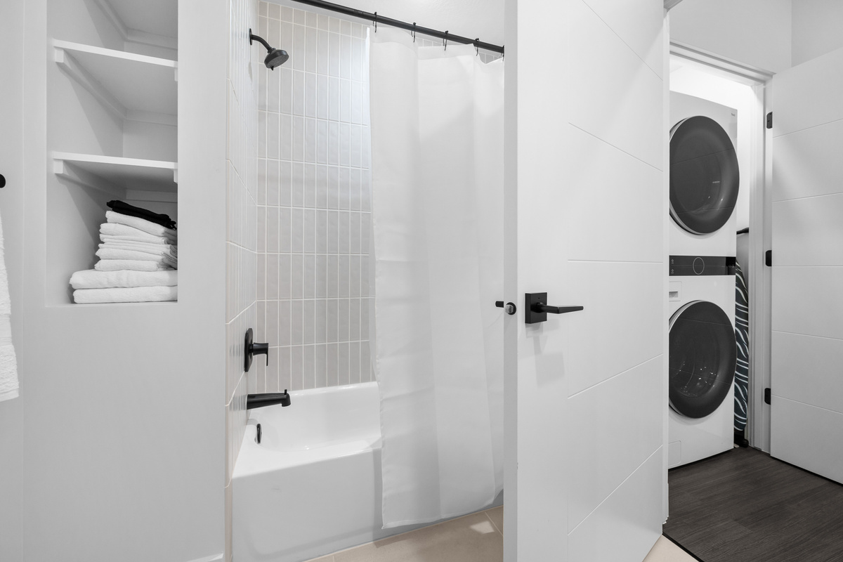 Fresh, bright bathroom with laundry access nearby.