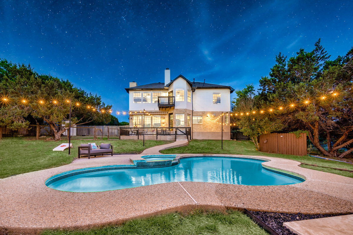 Curved pool glowing under string lights — a magical evening retreat.