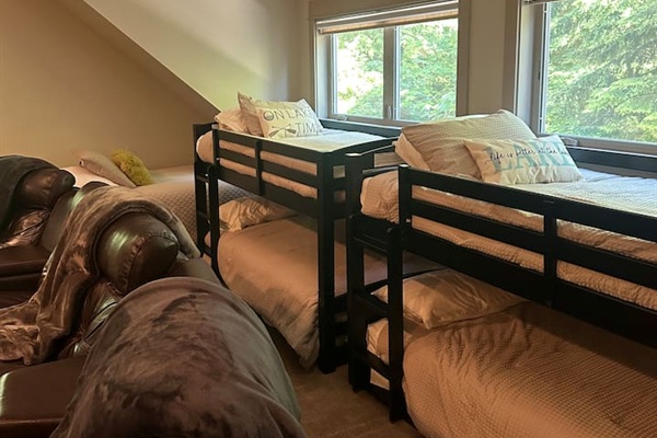 The bunk room sleeps five, featuring two low-profile bunk beds and an additional twin bed, creating a cozy retreat-like space. The twin bed can comfortably accommodate an adult, while the bunks are only suited for children.