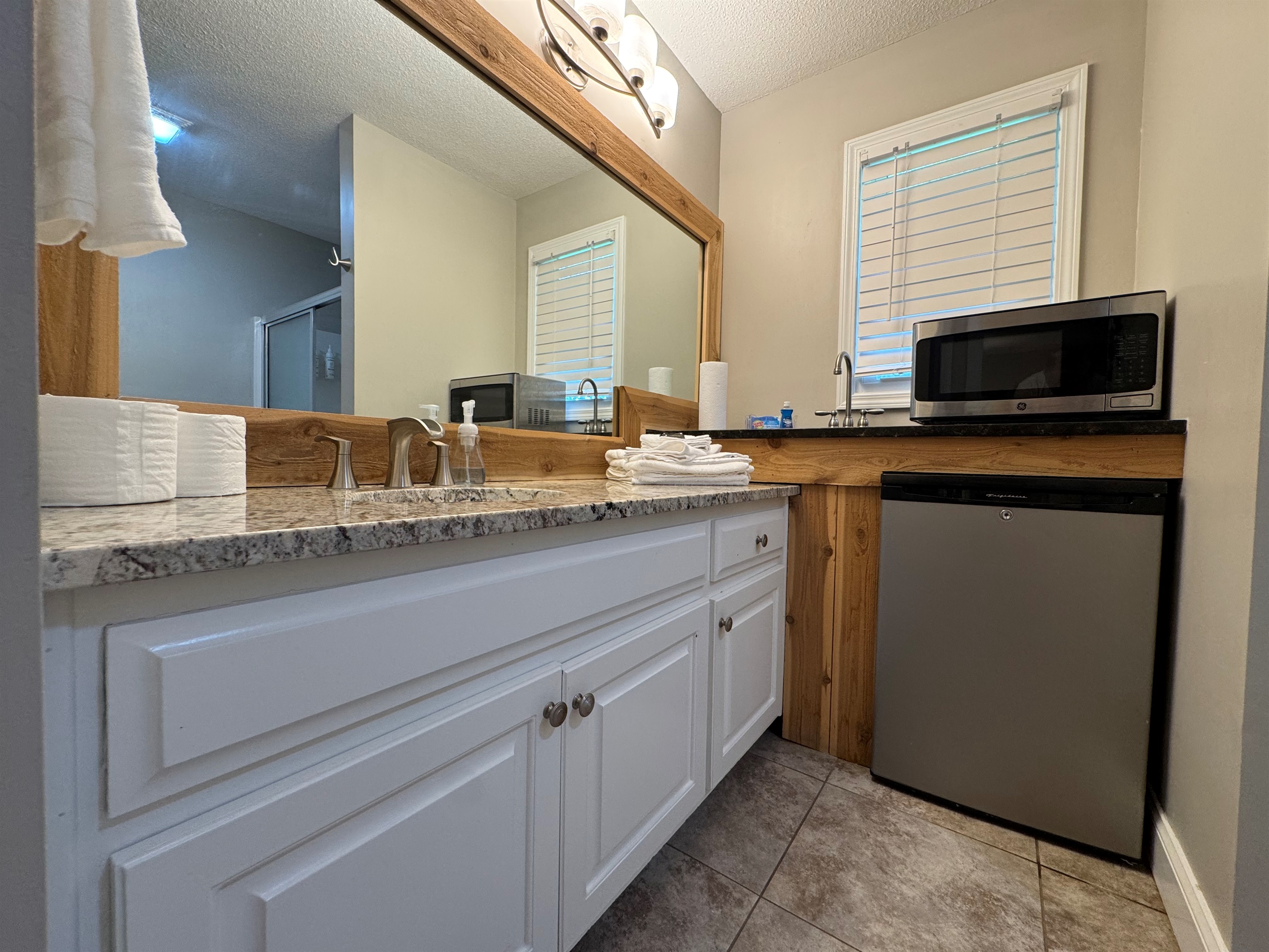 Unique setup with granite vanity and kitchenette area including a sink, fridge, microwave, and storage.