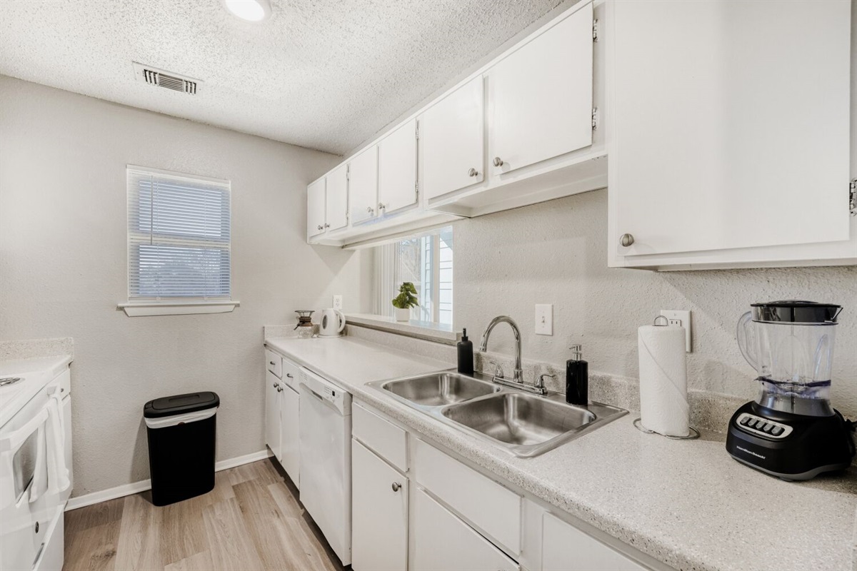 Bright galley kitchen with white cabinets, modern finishes, and plenty of counter space.