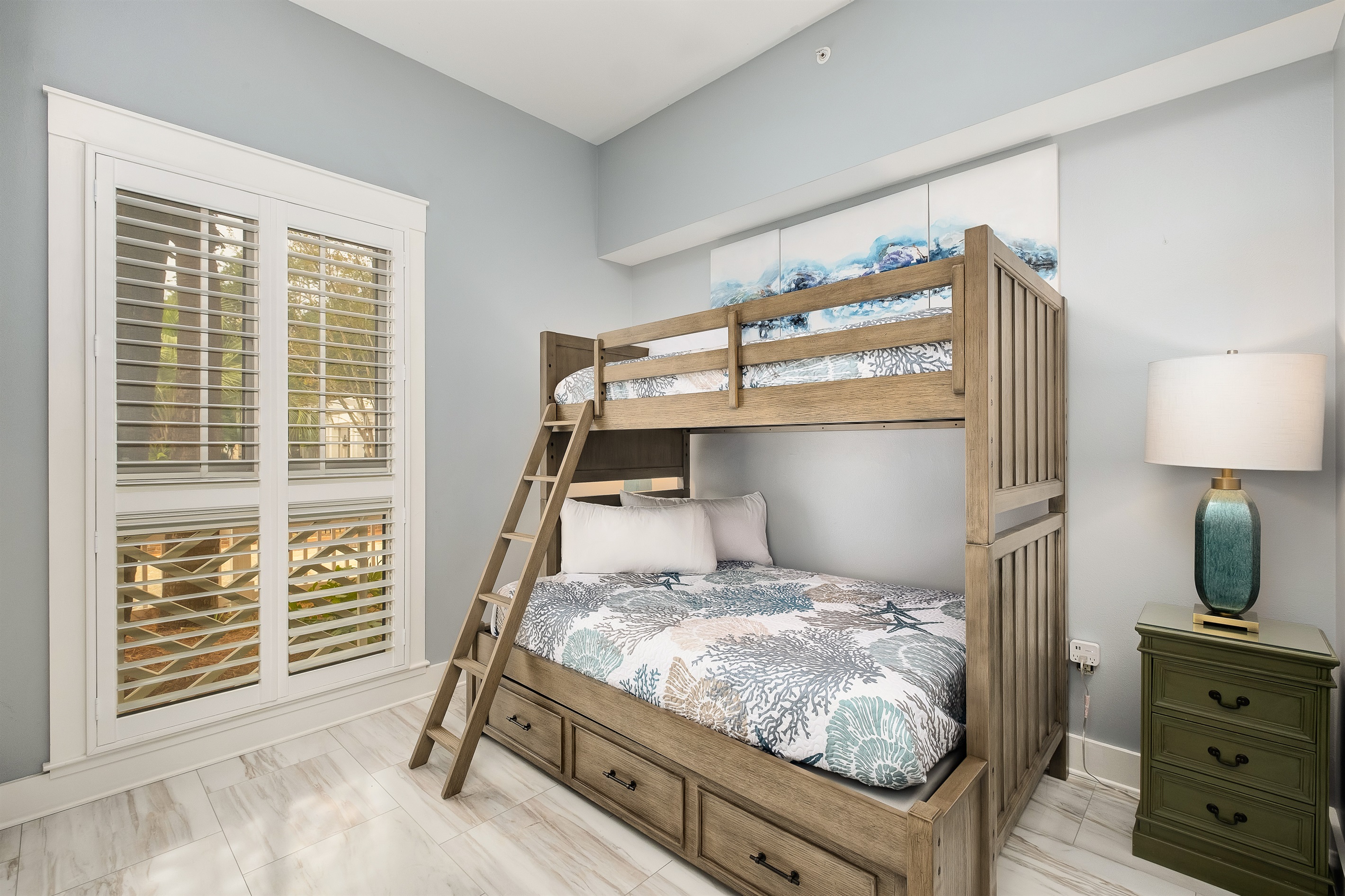Charming bunk bed setup with a double bed on the bottom and a twin bed on top, perfect for kids or extra guests. Natural light fills the room through large windows with plantation shutters.