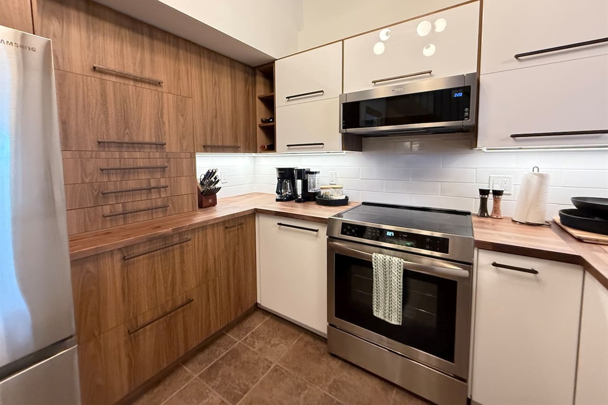 Modern Cooking Appliances: The kitchen boasts a sleek induction stove and range, a built-in dishwasher, and wood accents, making meal prep a breeze during your mountain getaway.