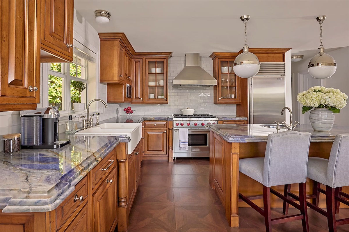 Custom chef’s kitchen showcasing high-end appliances, a spacious farmhouse sink, and stunning Blue Bahia marble countertops.