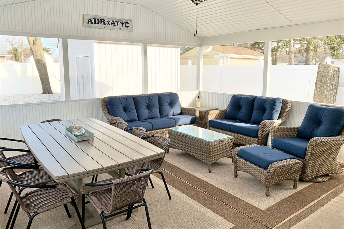 Experience the best of indoor-outdoor living in our screened-in sunroom. Kick back on navy wicker seating to watch the game or enjoy a meal at the large dining table—all while staying protected from the elements in a bright, coastal setting.