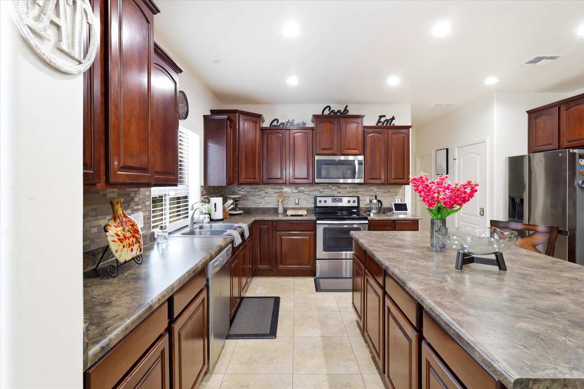 Kitchen with dark wood cabinets, a center island, full appliances, and lots of space for cooking.

