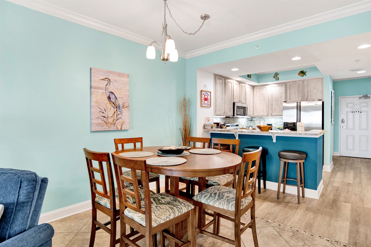 Dining area that has a table with 4 chairs and 3 additional seats at the breakfast bar