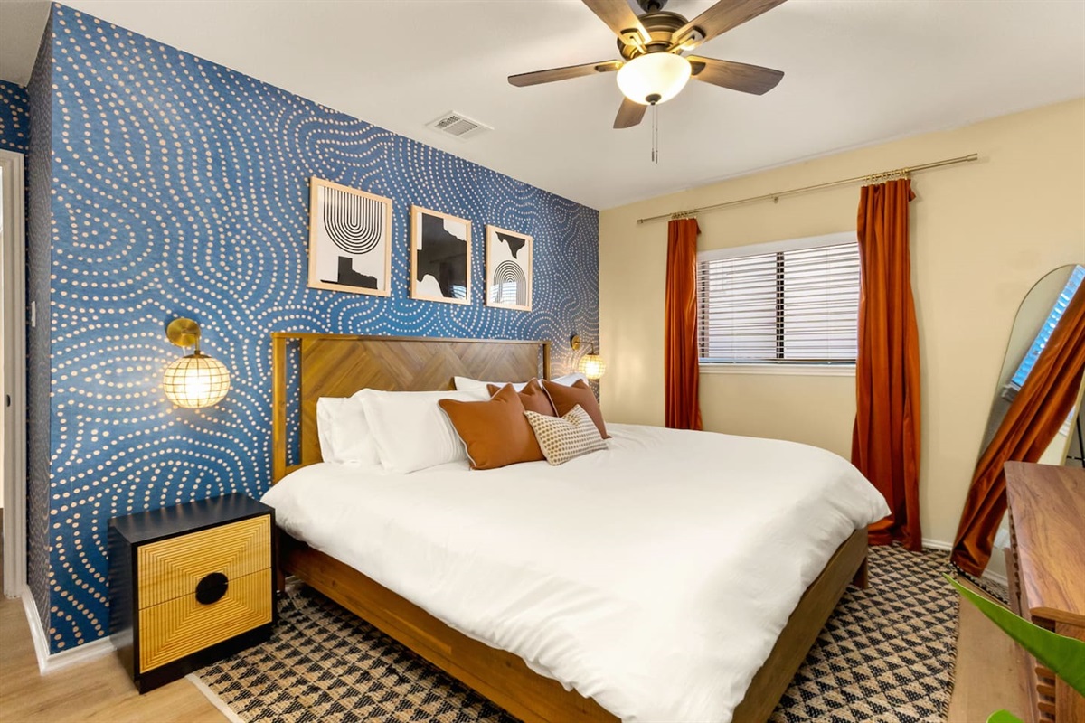 Modern meets cozy in this bold, art inspired king bedroom. With luxe bedding, warm tones and eye catching style, it's a peaceful retreat after exploring downtown, attending a wedding or working a long shift.