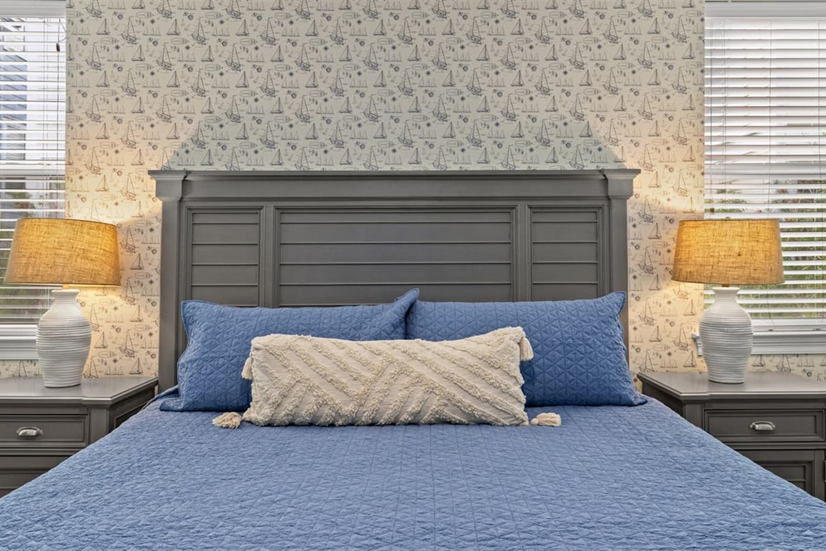A king bed retreat with coastal wallpaper and soft blue tones