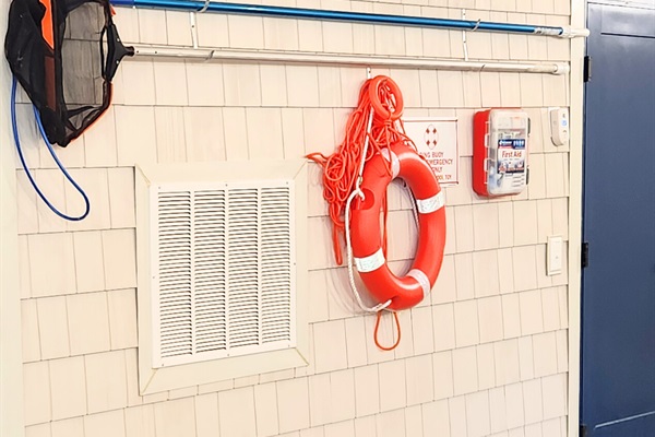 Indoor pool equipped with required safety equipment including life ring, rescue rope and first aid kit.