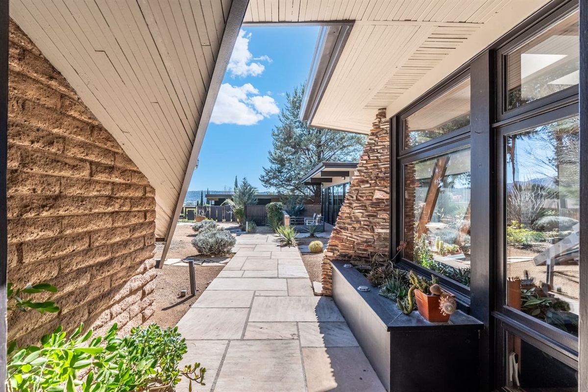 Covered walkway with clean architectural lines, stone accents, and floor-to-ceiling windows.