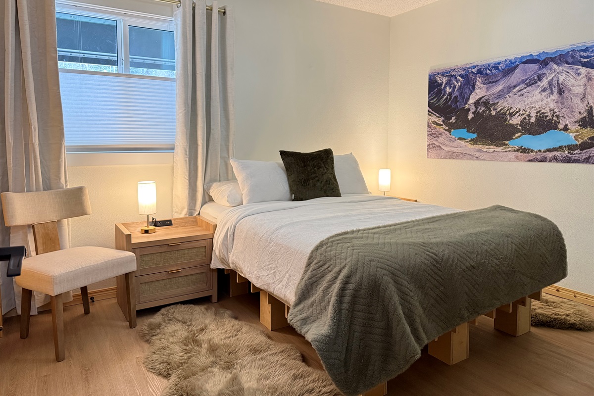 Cozy queen bed with dual nightstands featuring outlets, USB and USC ports, and dimmable touch lamps for a comfortable, connected stay. 