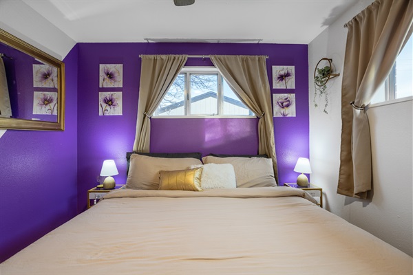 A purple room outfitted with ample pillows for relaxation, complemented by a mirror to add depth and brightness to the space.