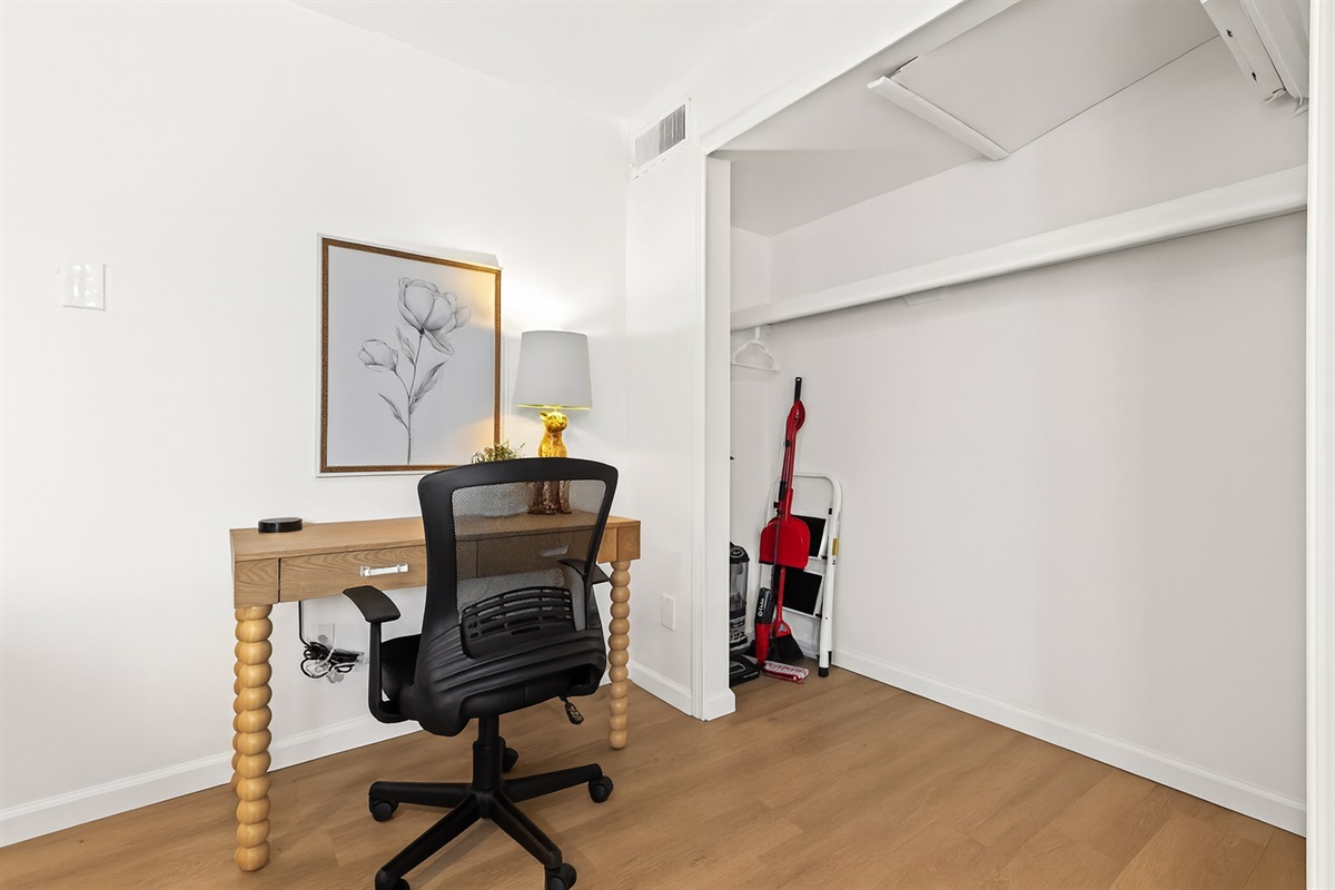 Functional workspace with a rivet-trimmed desk, mesh chair, and cozy lamp—ideal for productivity.