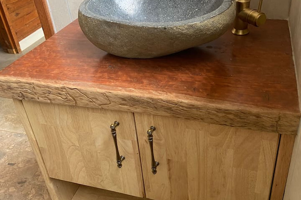 Natural timber, stone and brass finishes give the bathroom a calm, grounded feel during your Bob’s River House stay.