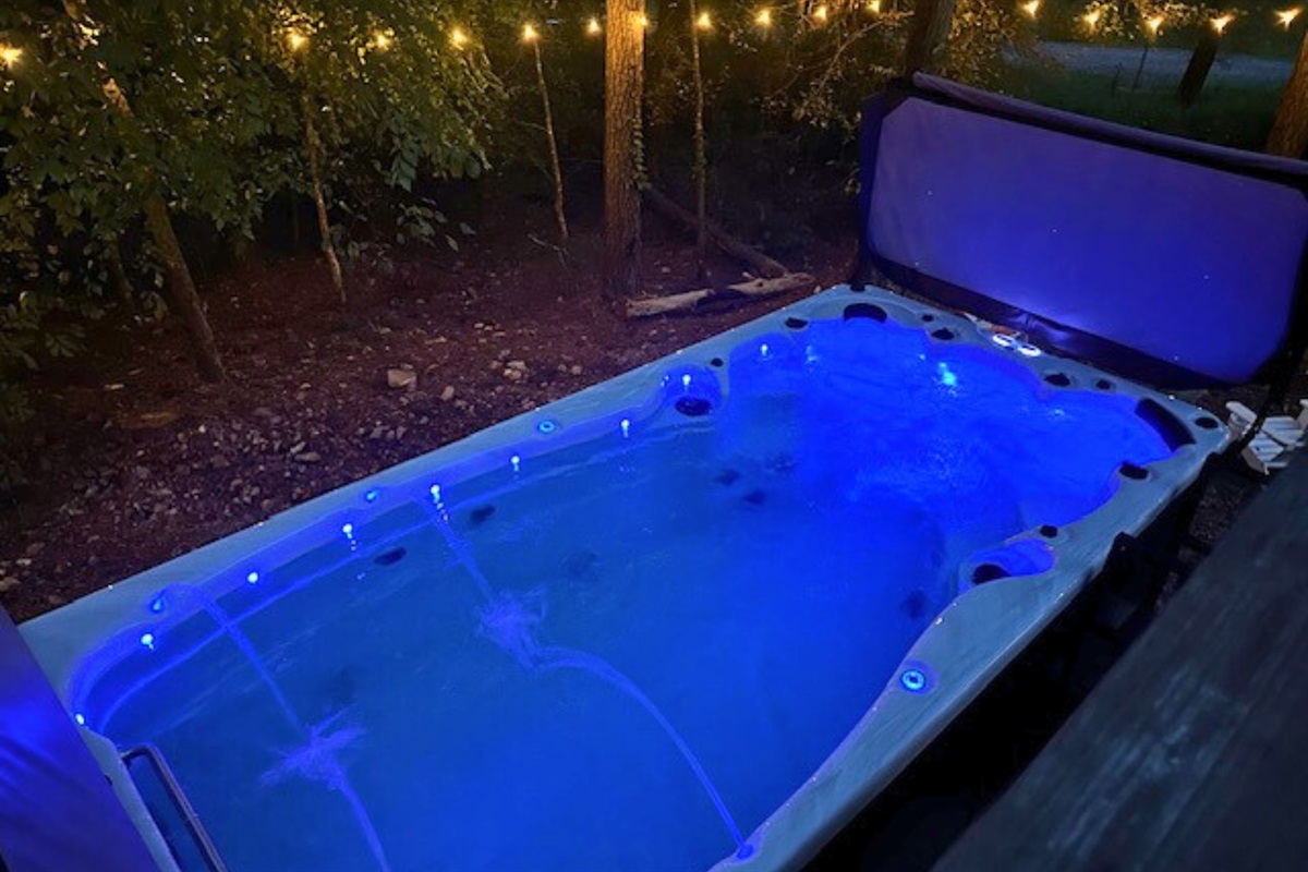 Take a dip in the glowing swim spa under string lights and forest views—perfect for relaxing nights.