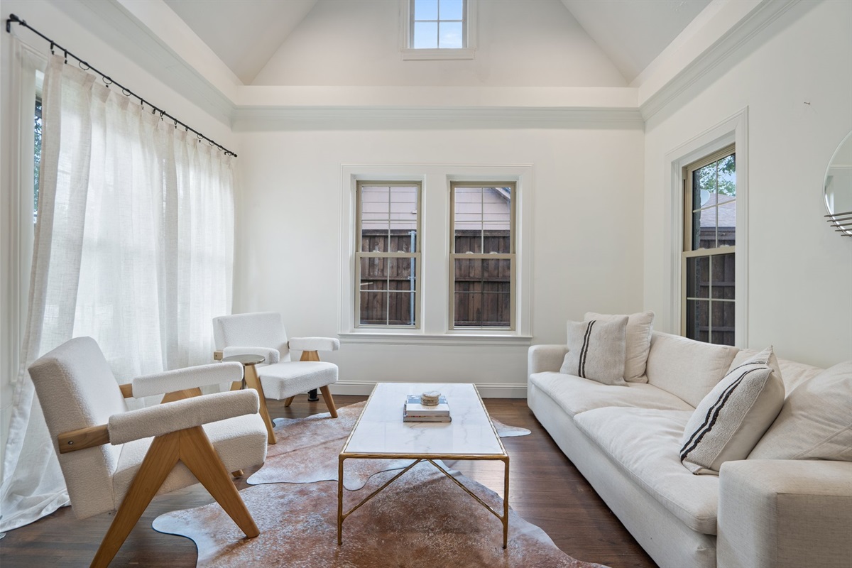 Living room seating area with neutral sofas, coffee table, and oversized windows. 55-inch Smart TV, high-speed Wi-Fi, central AC and heat, and portable fans. Comfortable open layout for groups.