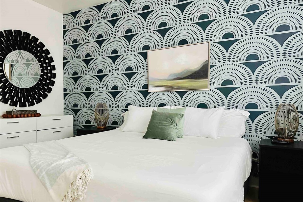 Upstairs king size bed with luxurious linens and art deco lamps, mirror, and accent wall. Watch TV from bed!