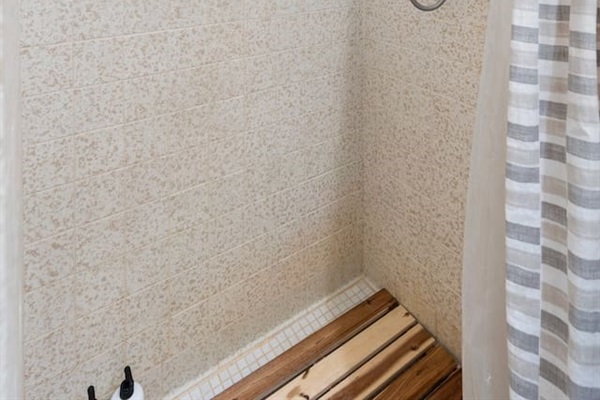 Walk-in shower with handheld sprayer and wood tile floor adds rustic charm to your daily routine.