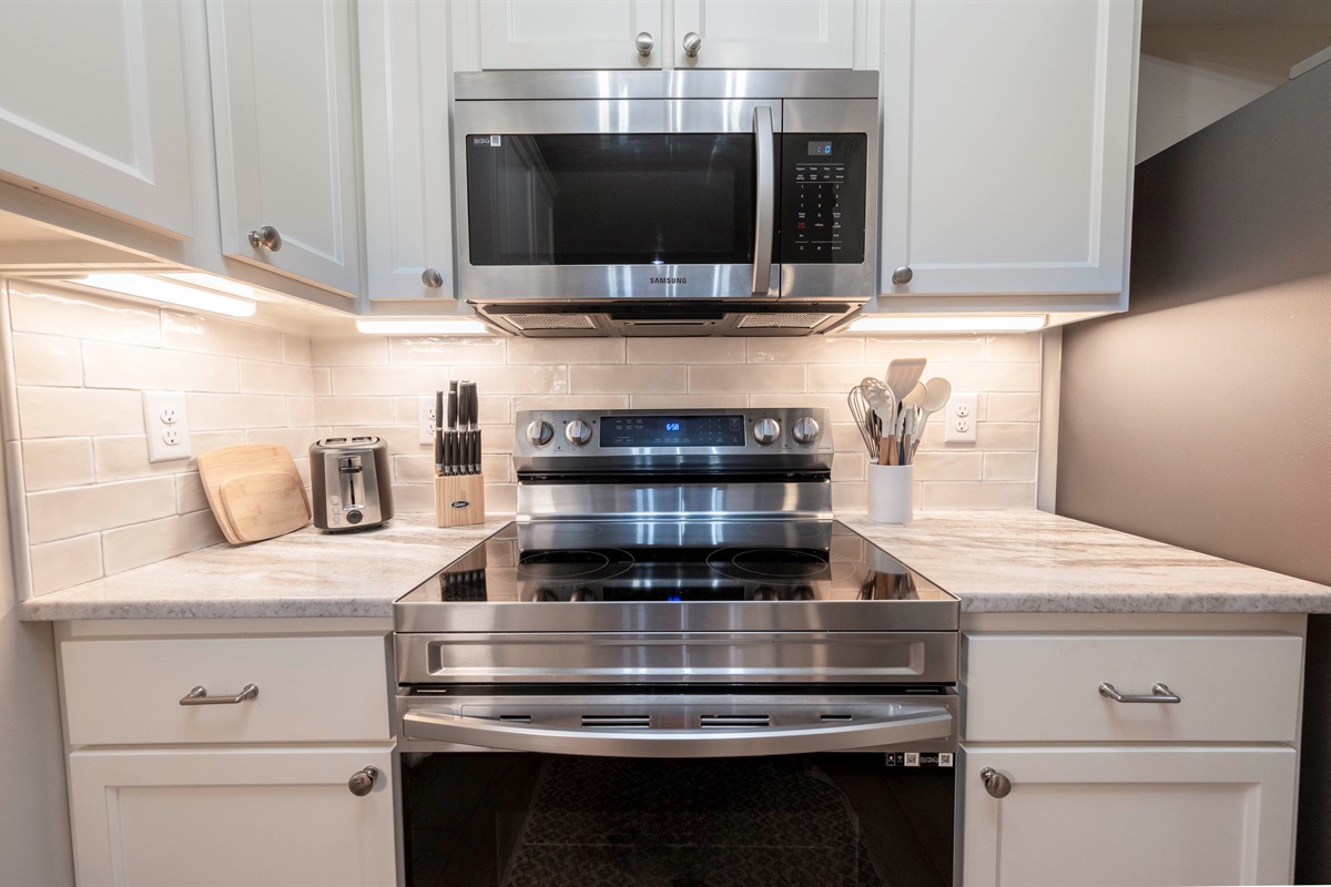 All your basic kitchen utensils are ready to use in this modern space with a sleek stovetop and oven.