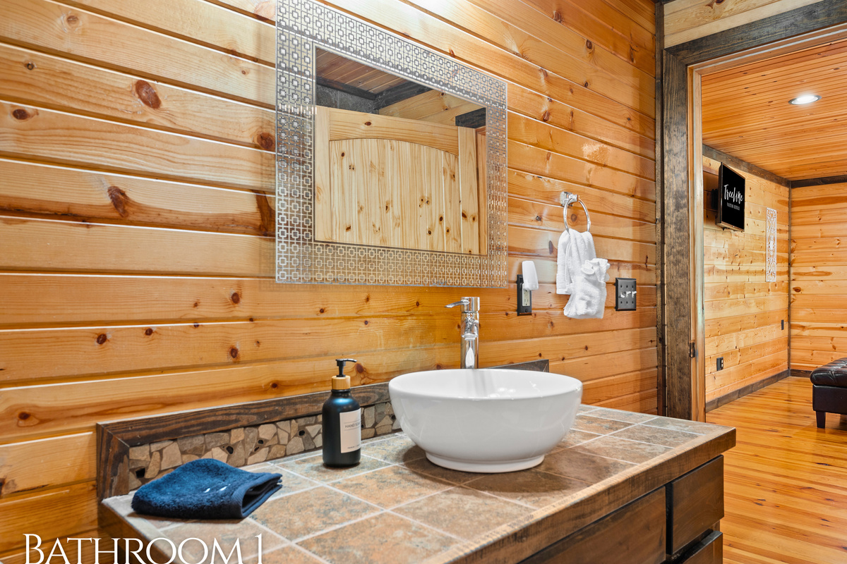Natural wood, a vessel sink, and thoughtful touches give Bathroom 1 a spa-like feel tucked inside a cozy cabin.