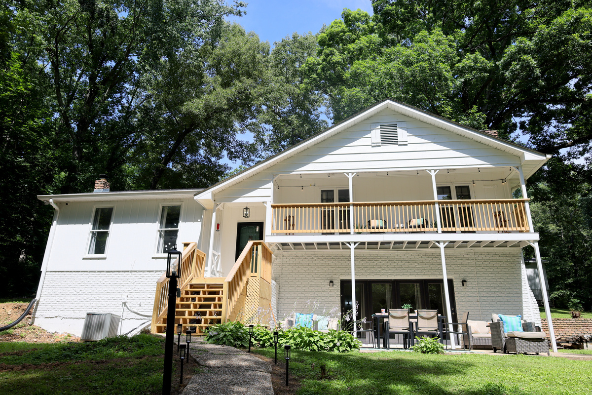 Exterior view of the lake house with spacious decks, outdoor seating, and wooded surroundings