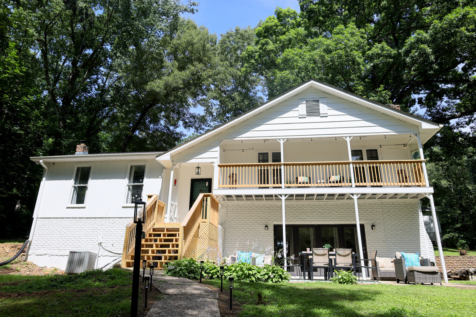 Exterior view of the lake house with spacious decks, outdoor seating, and wooded surroundings