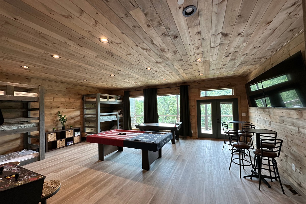 Rustic charm meets game night goals. This spacious game room is made for pool tournaments, friendly competition, and laid back hangs, all wrapped in warm wood tones and forest views just beyond the doors.