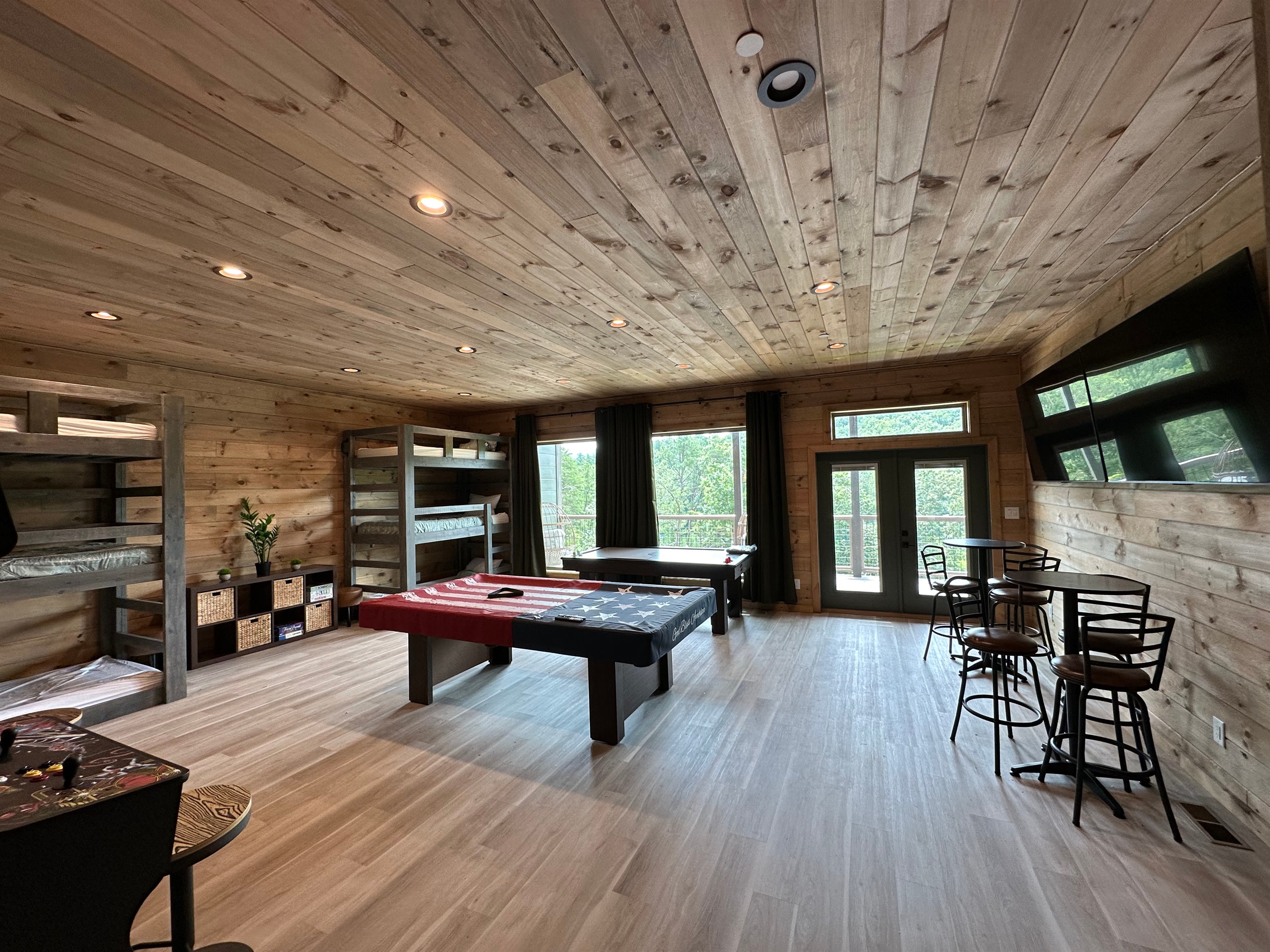 Rustic charm meets game night goals. This spacious game room is made for pool tournaments, friendly competition, and laid back hangs, all wrapped in warm wood tones and forest views just beyond the doors.