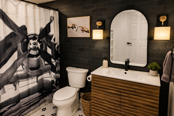 Private basement bathroom with a walk-in shower, modern vanity and bold aviation-inspired wall art.