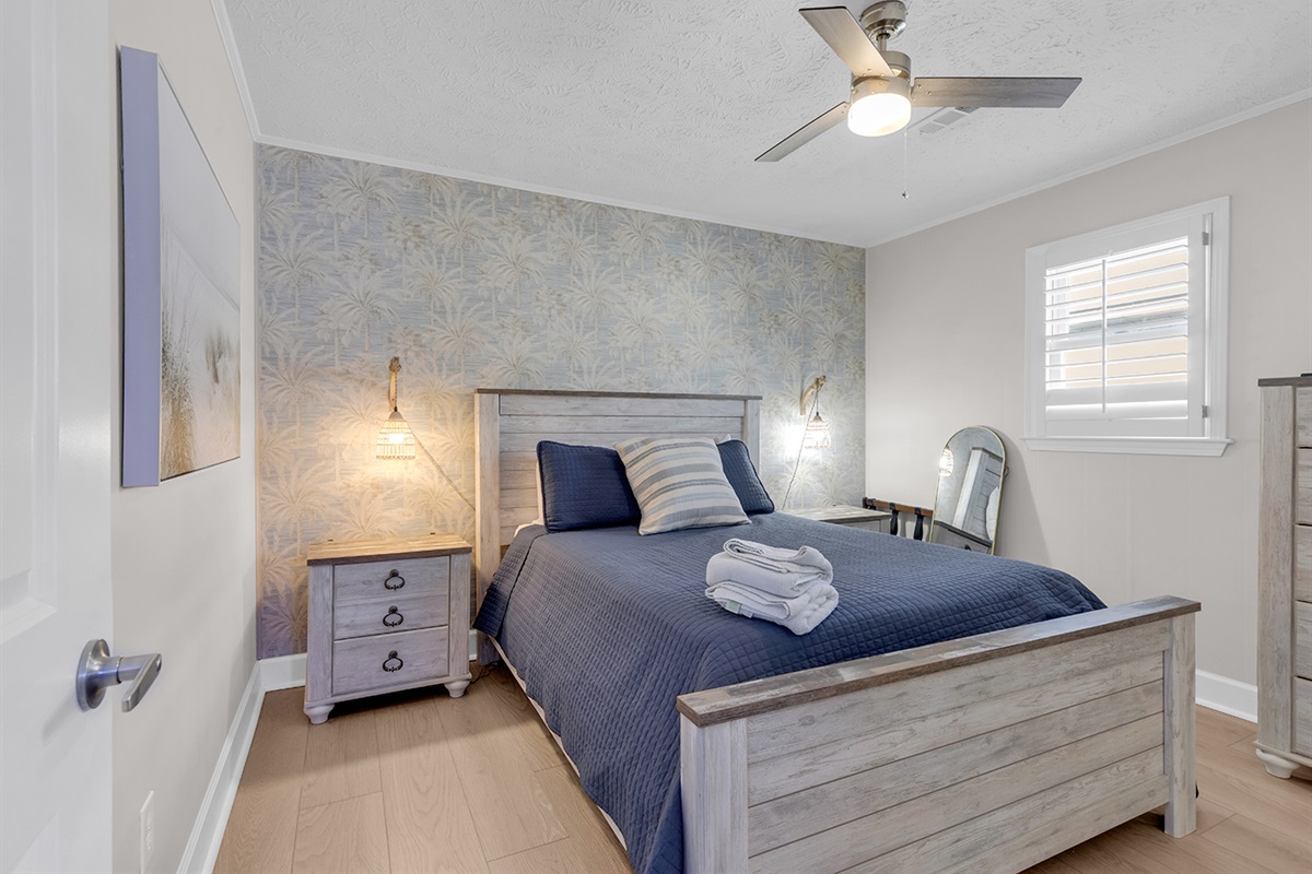 Bedroom 2 with Queen bed and tasteful wallpaper background.