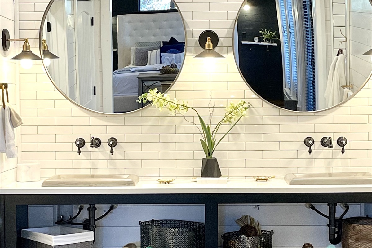 Your first glimpse of the large bathroom in First Kiss. Dual large round mirrors reflect plenty of light throughout the large bathroom. Fancy wall-mounted faucets and plenty of storage space for your personal items.