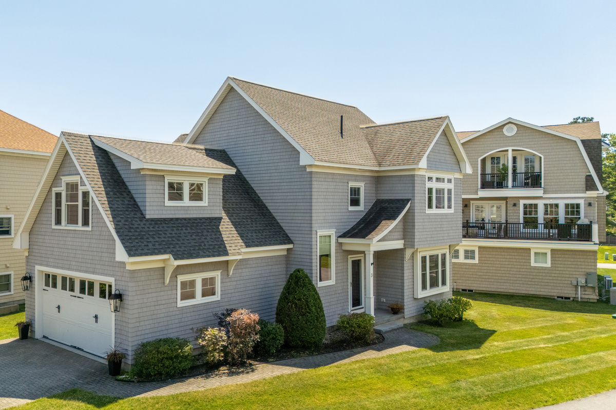 A beautiful coastal exterior surrounded by well-kept grounds and neighboring beach homes.