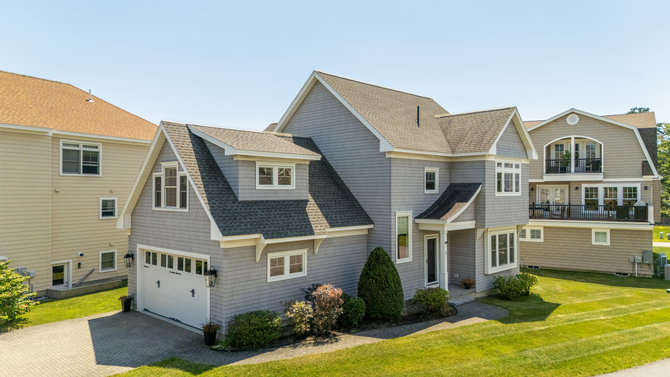 A beautiful coastal exterior surrounded by well-kept grounds and neighboring beach homes.