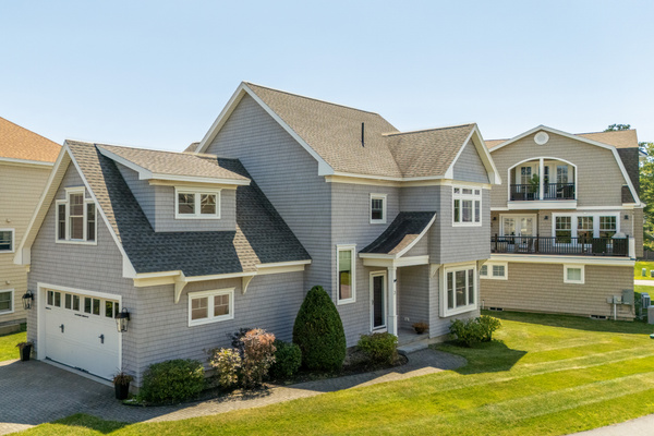 A beautiful coastal exterior surrounded by well-kept grounds and neighboring beach homes.
