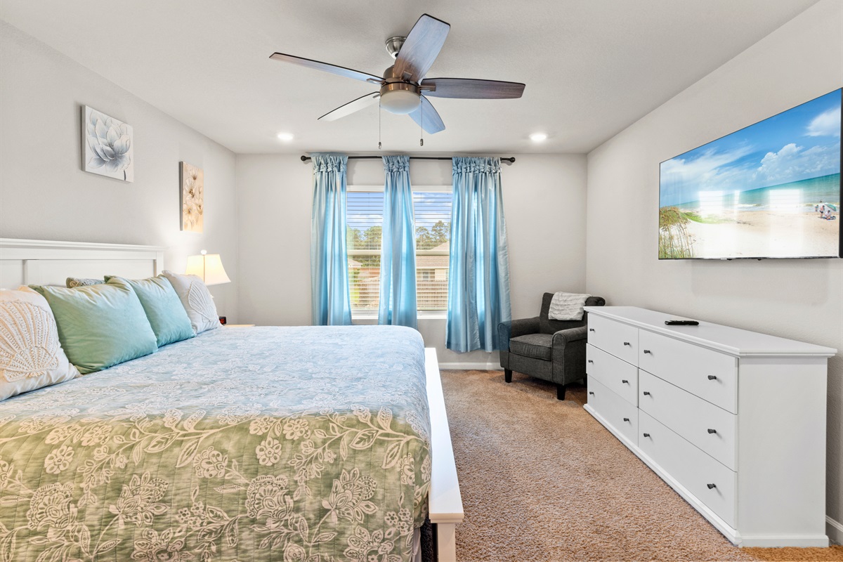 Relax in the serene primary bedroom with calming coastal hues, king bed, and natural light streaming through the windows.