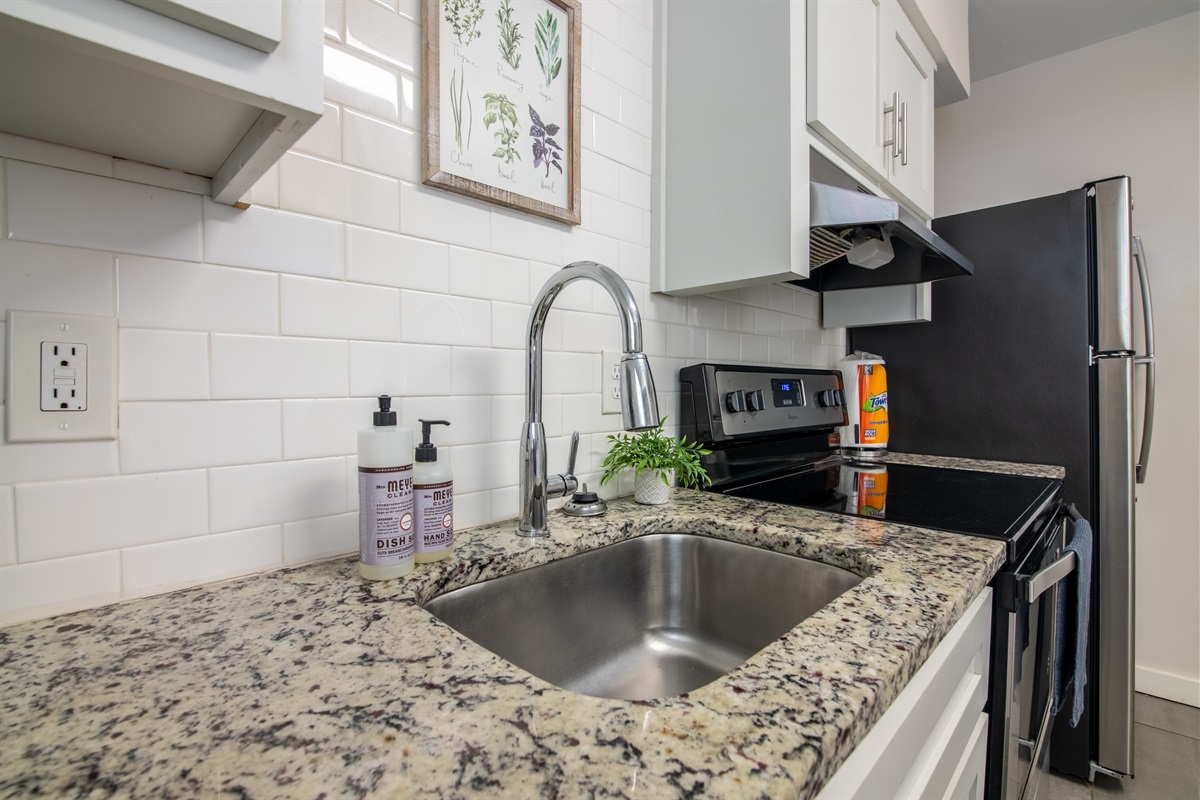 Sleek and simple kitchen sink area with modern finishes and under-cabinet lighting.