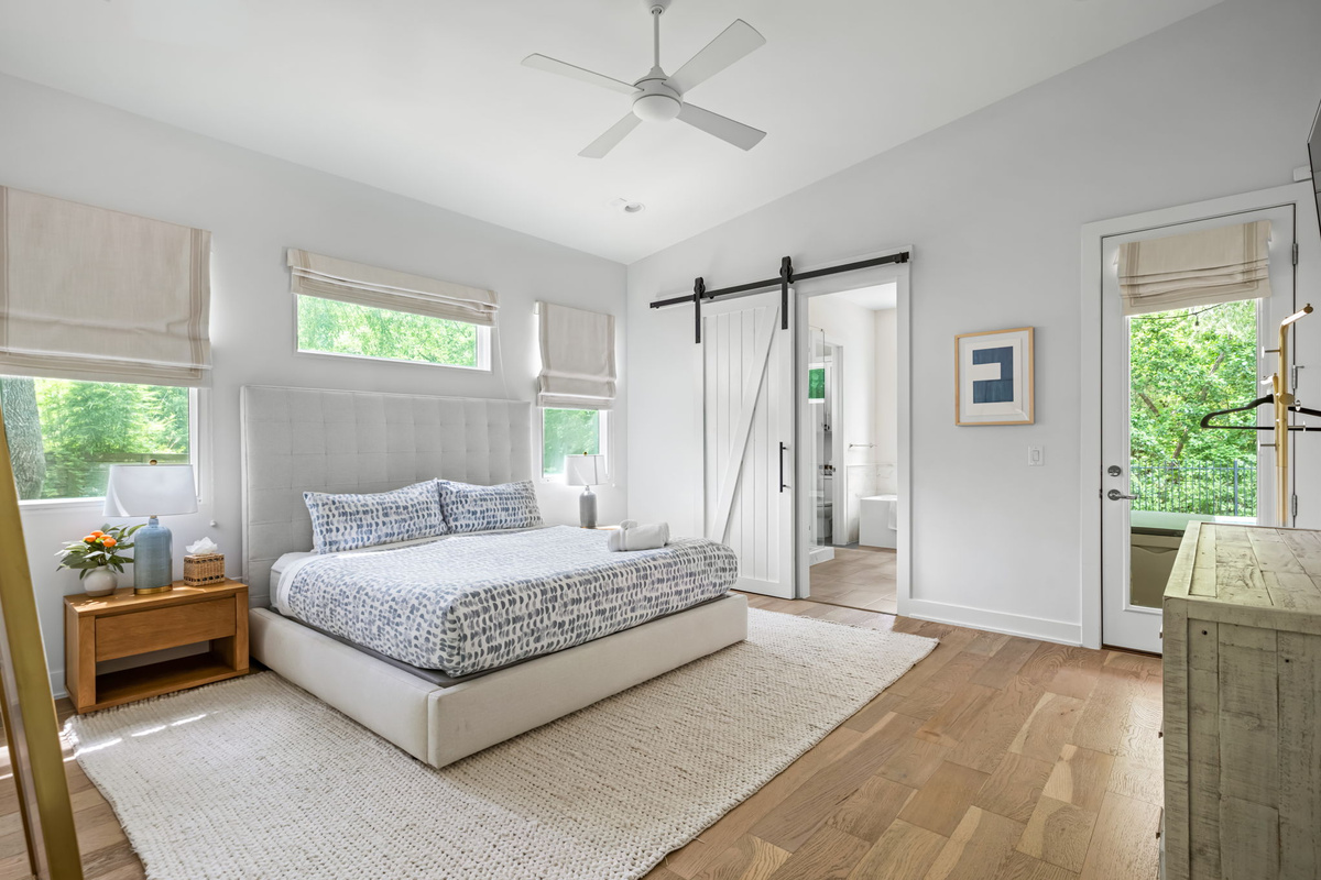 Serene primary bedroom with vaulted ceiling, ceiling fan, and elegant barn doors leading to a private ensuite — a peaceful retreat after a day of exploring.