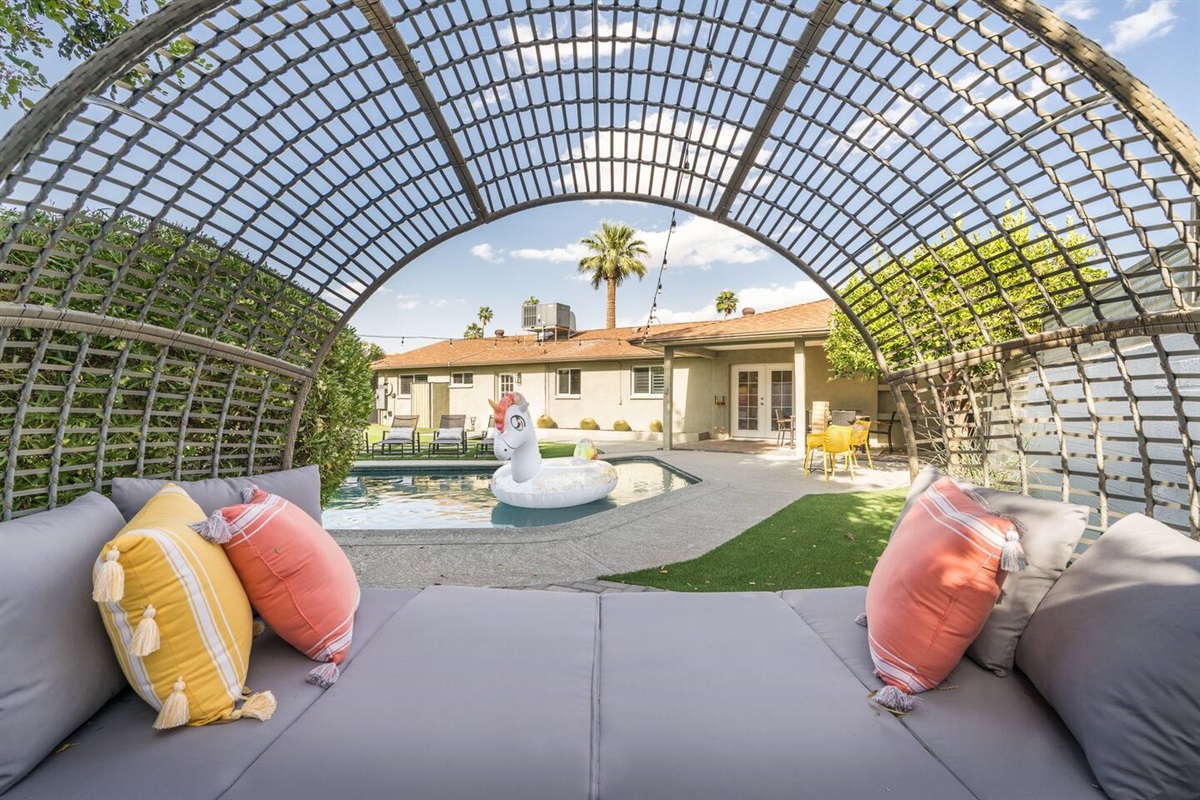 Huge back yard features large pool with Baja step; covered patio with dining table; putting green; gas fire pit;  sun loungers; Giant Jenga; and corn hole.Pool can be heated for an add'l fee.