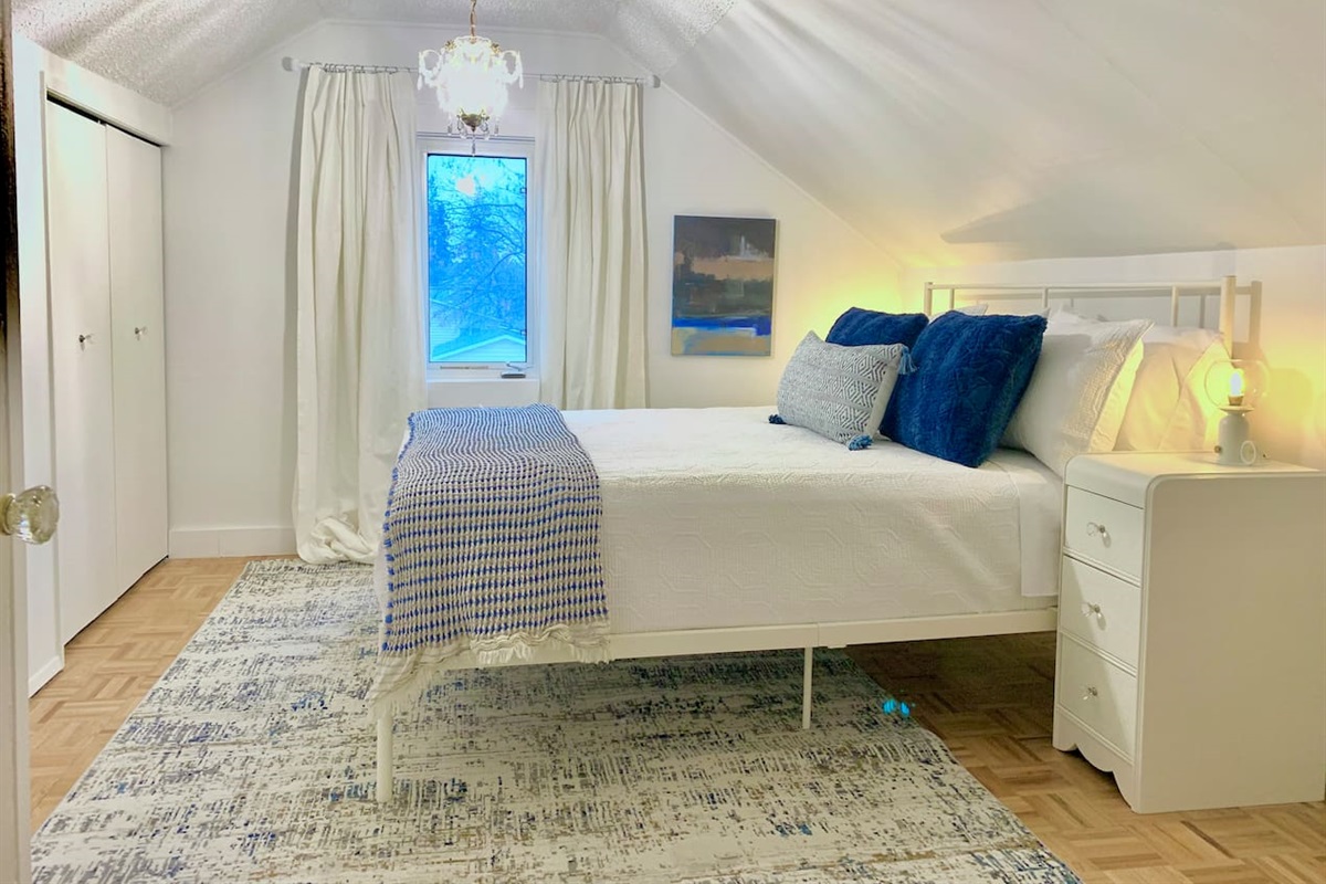 Primary bedroom located upstairs with queen bed, quality linens, and window coverings for a restful sleep.